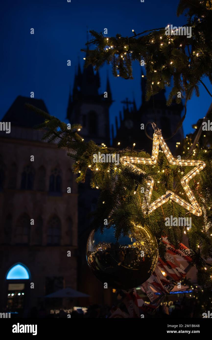 Prag, Tschechische Republik - 5. Dezember 2022: Vertikaler Blick auf die Sternendekoration auf dem Weihnachtsbaum mit der gotischen Kirche im Hintergrund am Abend. Stockfoto