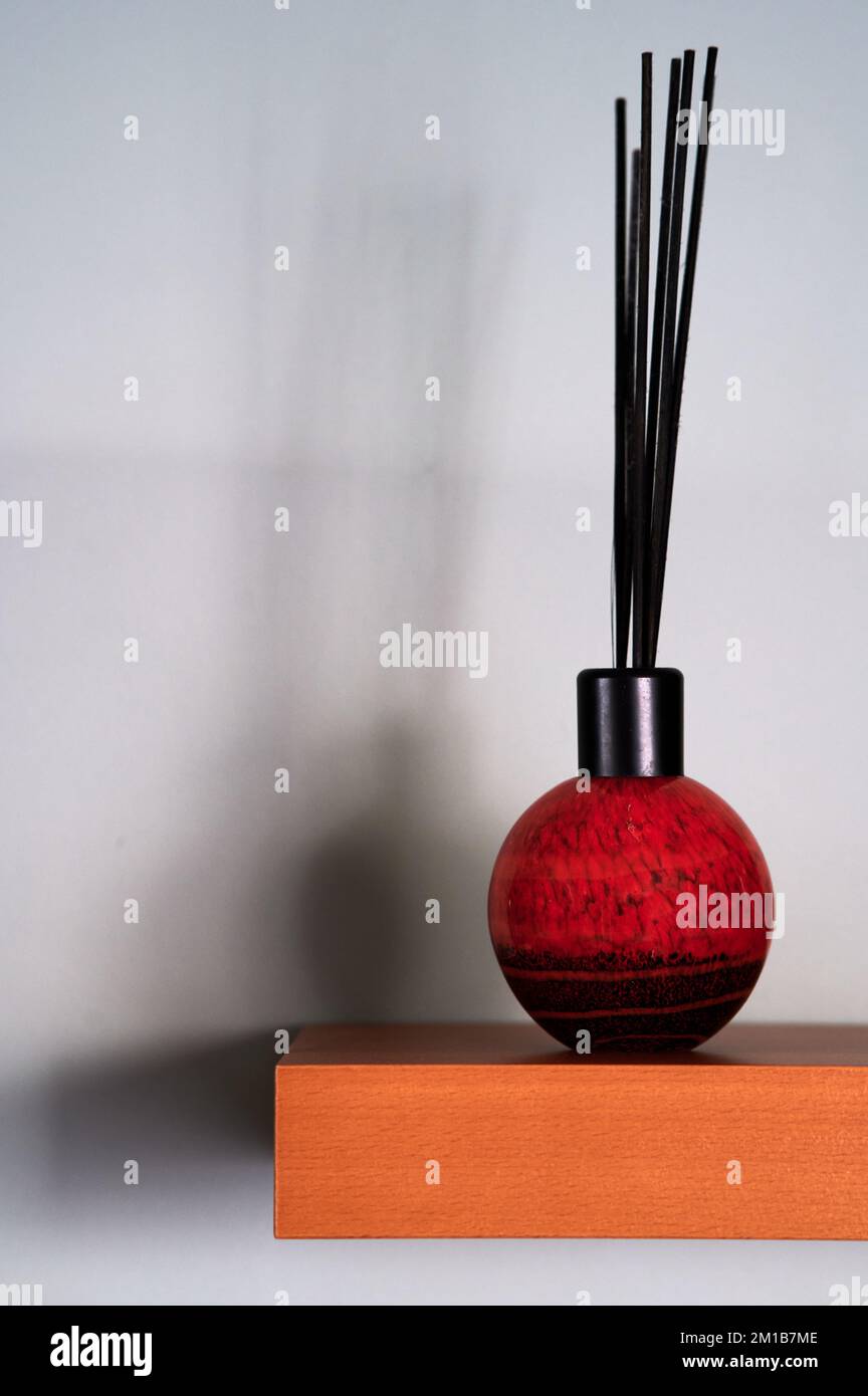 reed-Diffusor auf Holzregal mit Schatten an der Wand Stockfoto