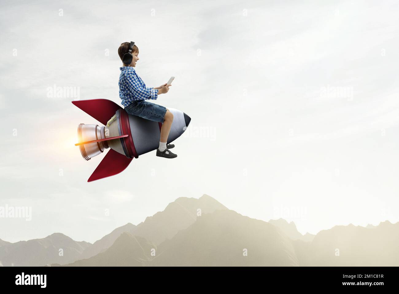 Kind trägt Kopfhörer auf einer Rakete Stockfoto