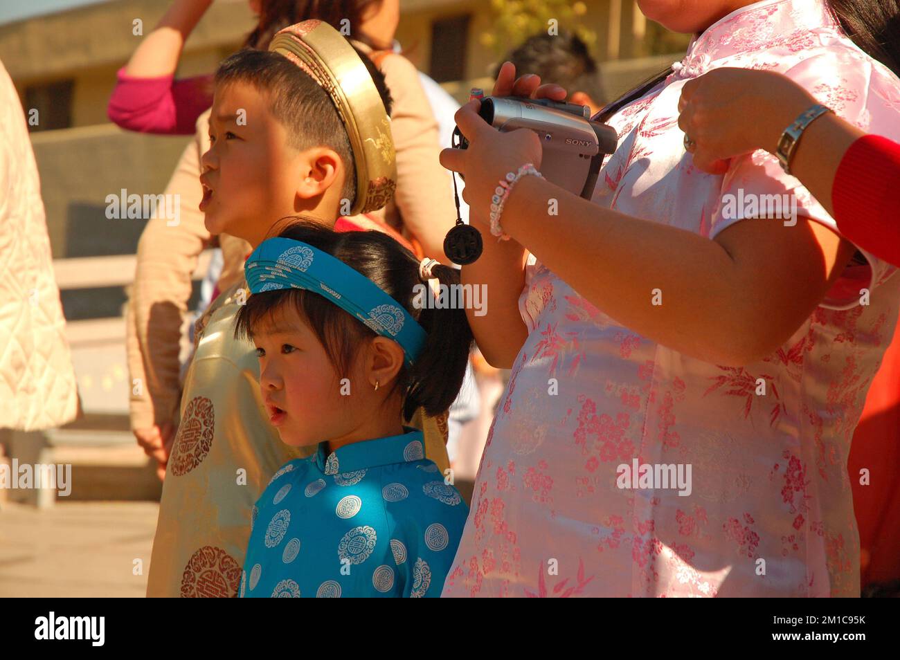 Kleine asiatische Kinder kleiden sich in traditioneller chinesischer Festkleidung und sehen sich die Feierlichkeiten zum Mondneujahr an Stockfoto