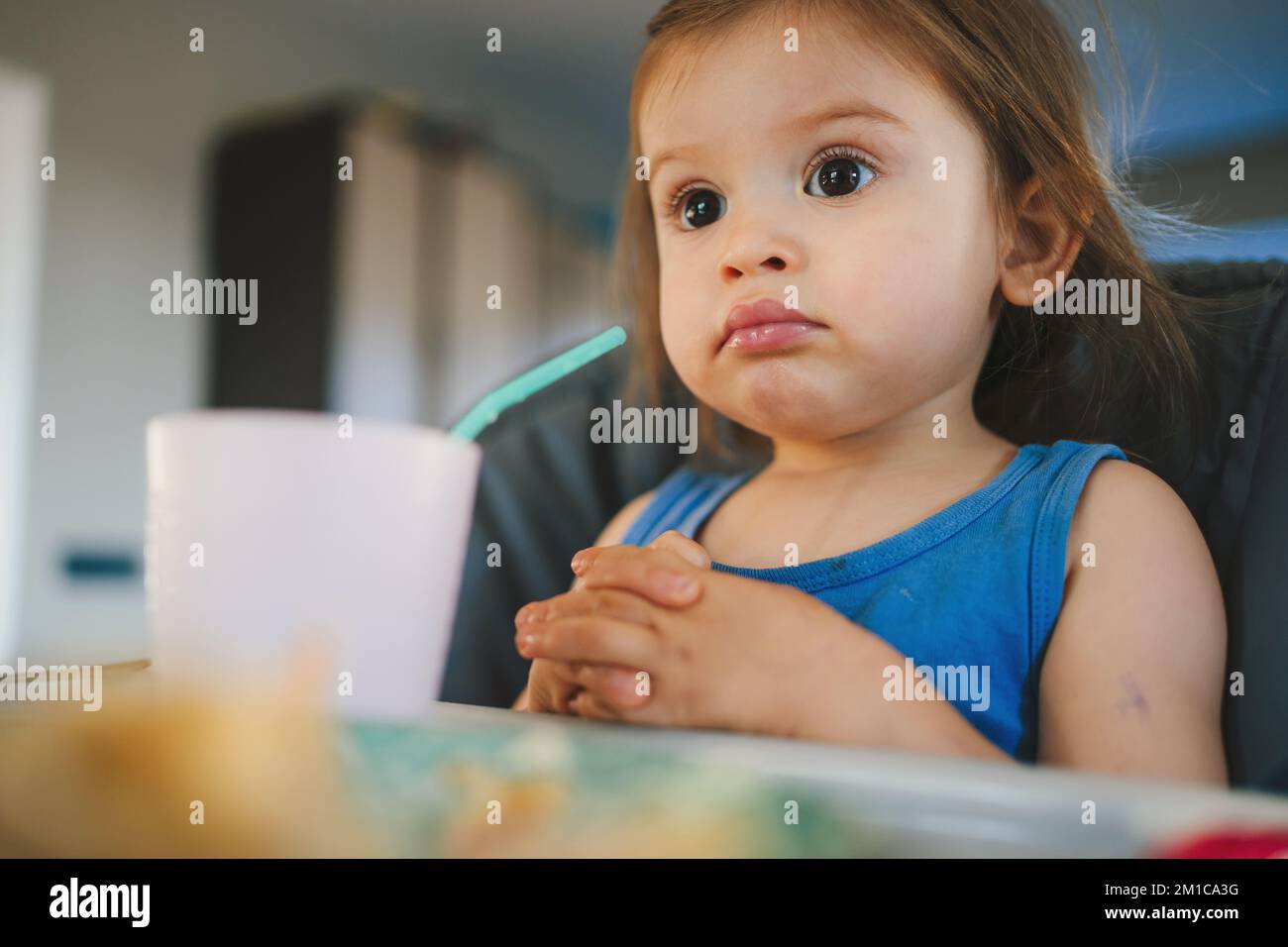 Porträt eines weissen Babymädchens, das im Hochstuhl zu Abend isst, selbsternähre feste Nahrung für Säuglinge. Wunderschönes Porträt. Glückliche Familie. Zeit für die Familie Stockfoto