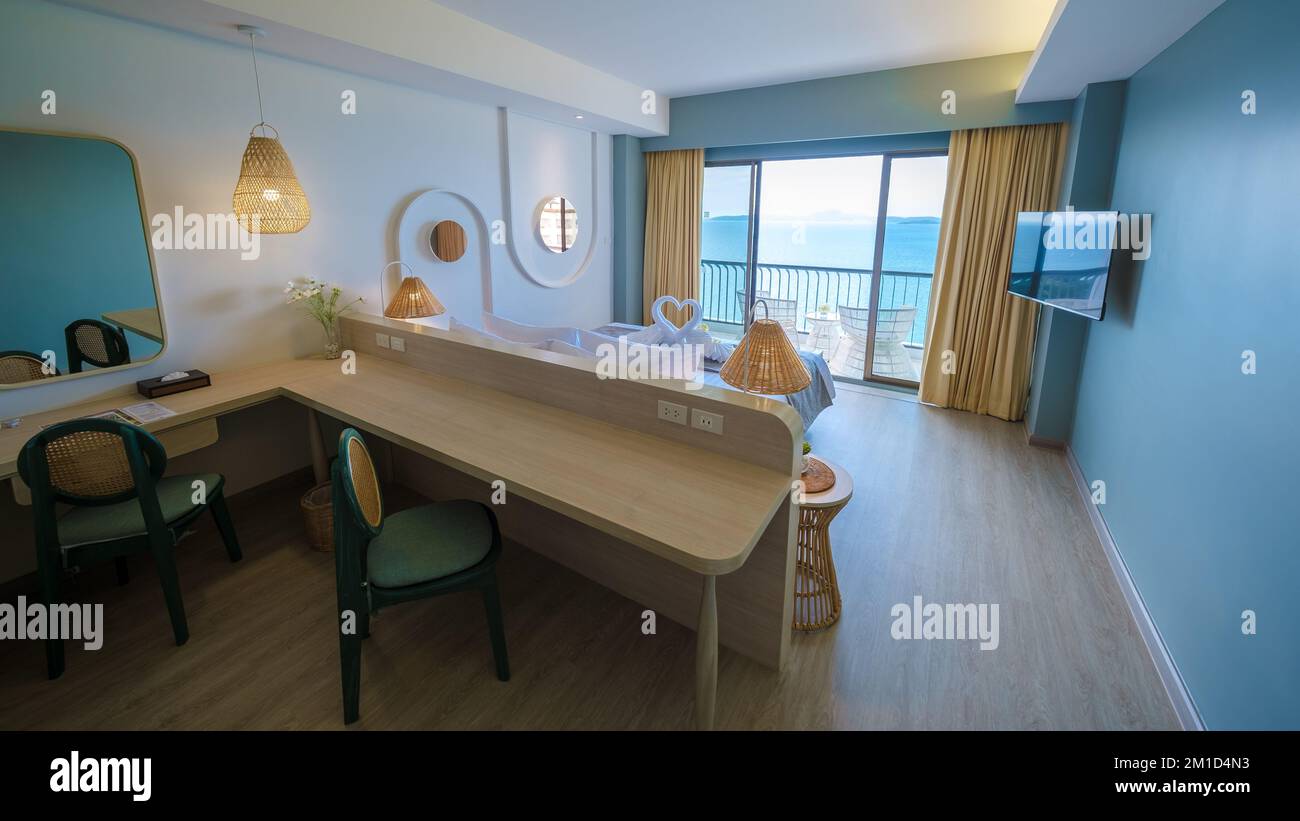 Ein Hotelzimmer mit hellen, frischen Farben im balinesischen Stil, minimalistisches Schlafzimmer mit blaugrüner Wand Stockfoto