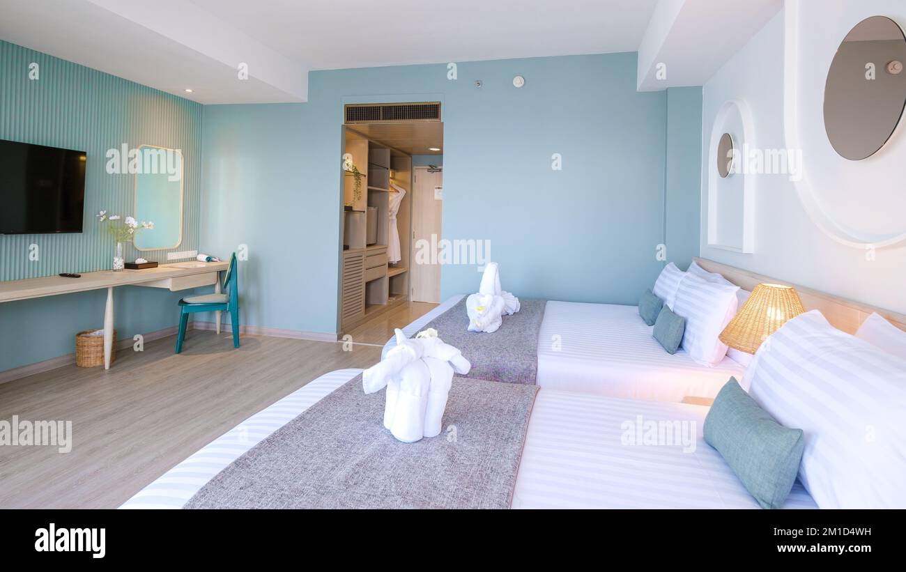 Ein Hotelzimmer mit hellen, frischen Farben im balinesischen Stil, minimalistisches Schlafzimmer mit blaugrüner Wand Stockfoto