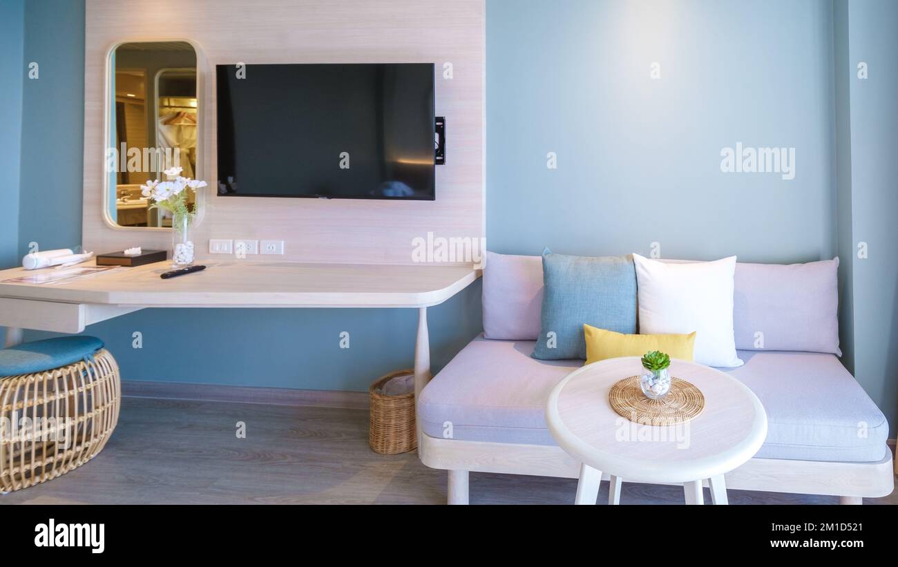Farbenfroher Sessel mit Kissen im Hotelzimmer in hellen, frischen Farben im balinesischen Stil, minimalistisches Schlafzimmer. Stockfoto