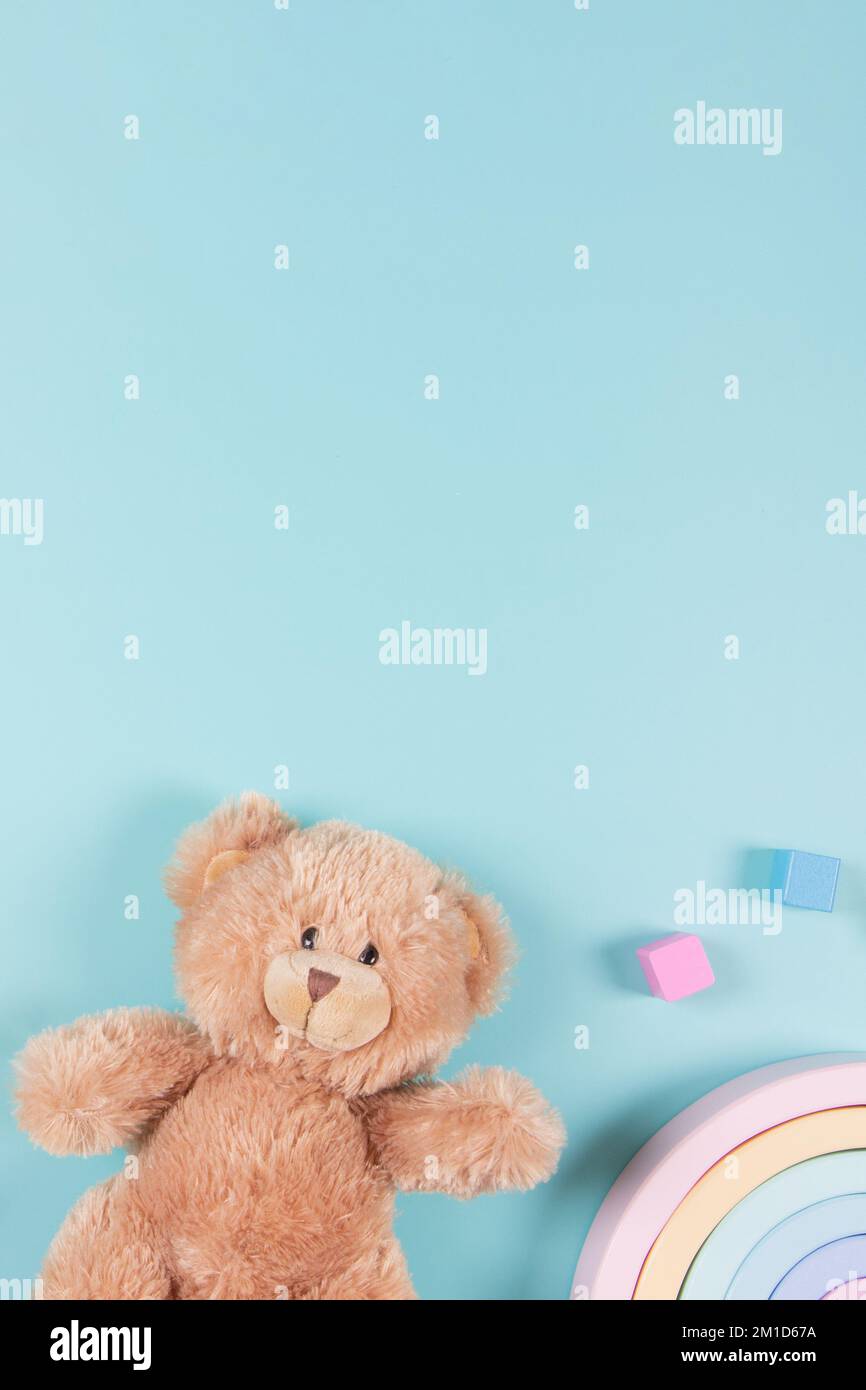 Lernspielzeug für Babys und Kinder – Hintergrund. Teddybär, Holzspielzeug mit Regenbogen und bunten Bausteinen auf hellblauem Hintergrund. Draufsicht, flach liegend Stockfoto