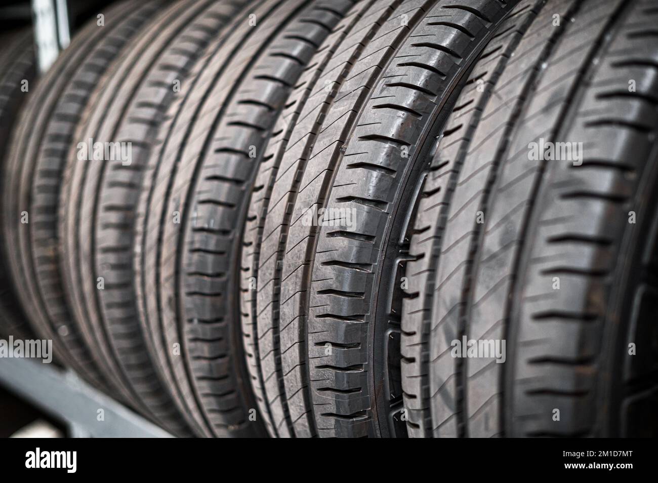 Metalltheke mit einer Reihe schwarzer Winterreifen, die im Wartungsraum aufbewahrt werden Stockfoto