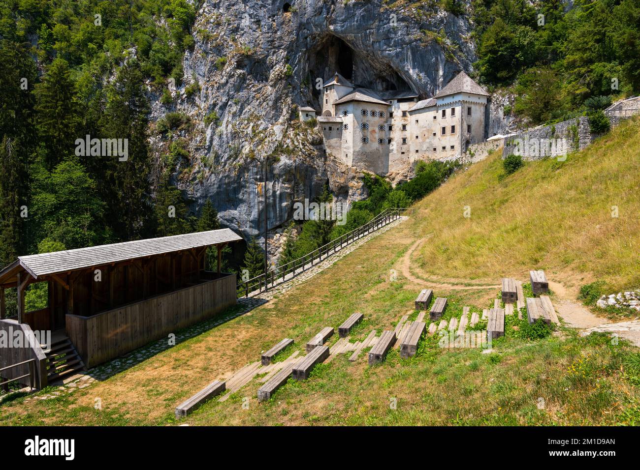 Landschaft mit mittelalterlichem Schloss Predjama in Slowenien. Die Höhlenburg in den Klippen mit einem Netz von geheimen Tunneln und dem Erazem Knight Tournament Ground mit Stockfoto