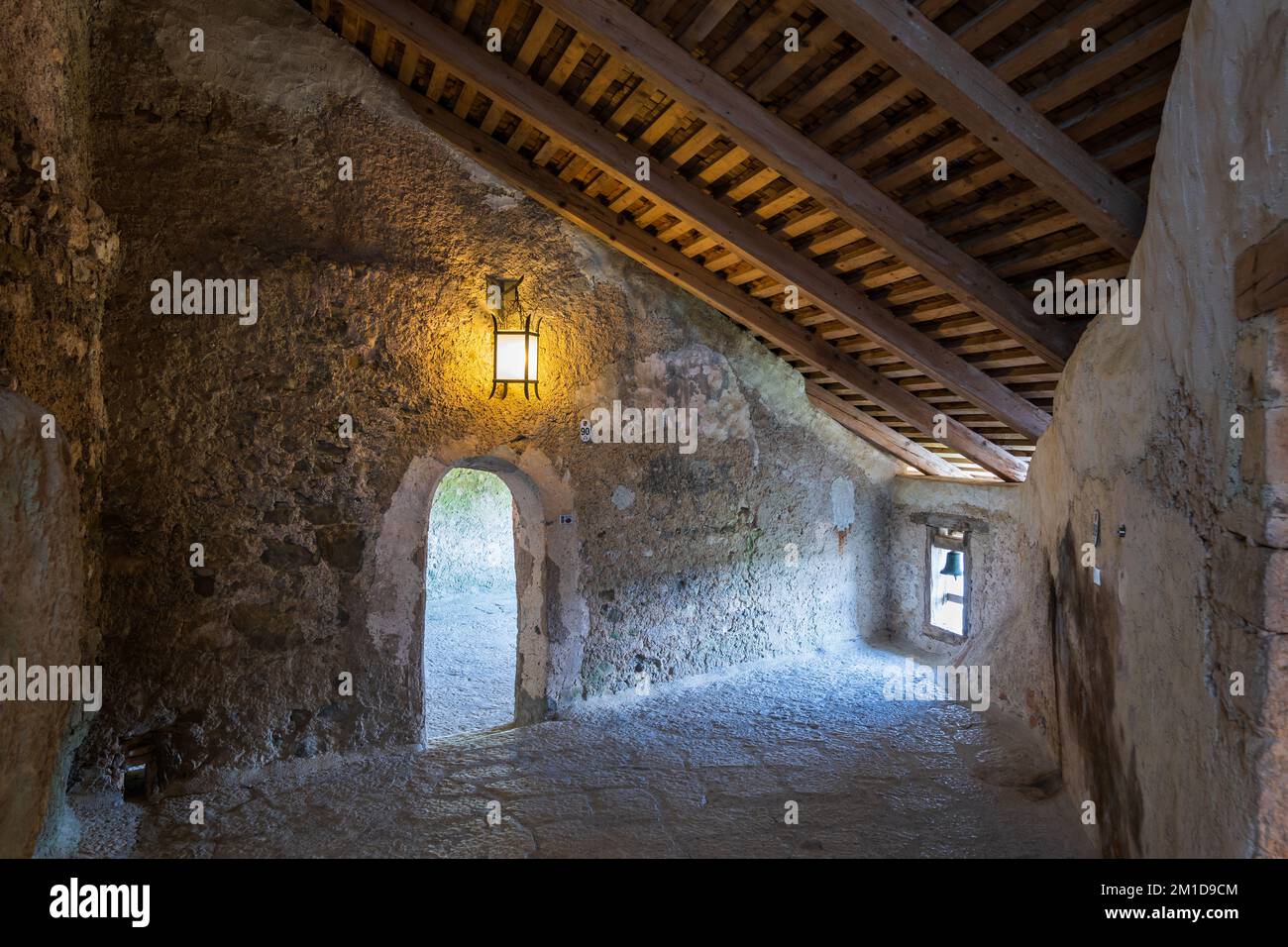 Mittelalterliches Interieur im Schloss Predjama, Slowenien, Zimmer mit Wunschglocke in einem winzigen, niedrigen Fenster in der Ecke. Stockfoto