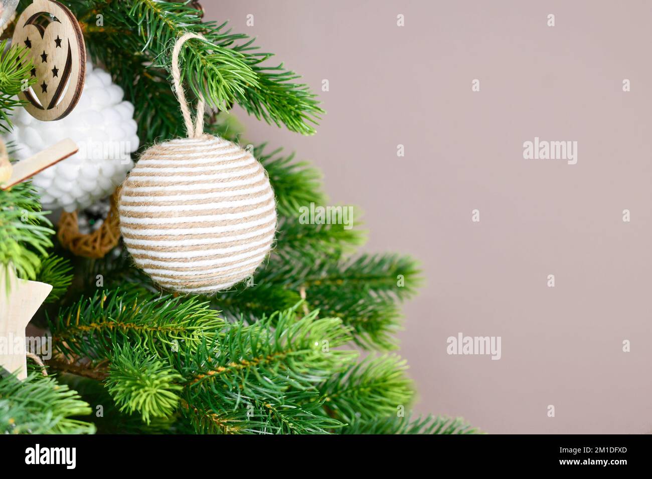 Christbaumzweige mit natürlicher Schmuckkugel aus beigefarbenem Juteseil mit Kopierbereich Stockfoto