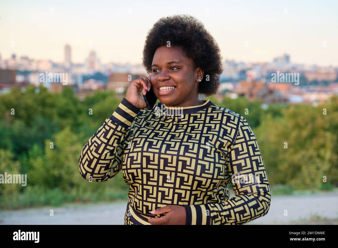 Junge afrikanische Frau lächelt und redet auf dem Smartphone auf der Straße. Stockfoto