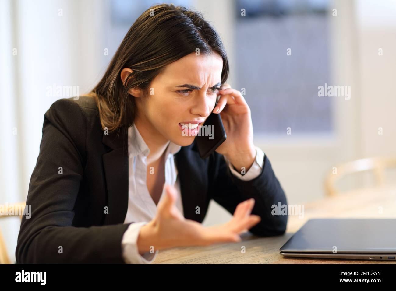 Wütende Geschäftsfrau, die telefonisch im Büro klagt Stockfoto