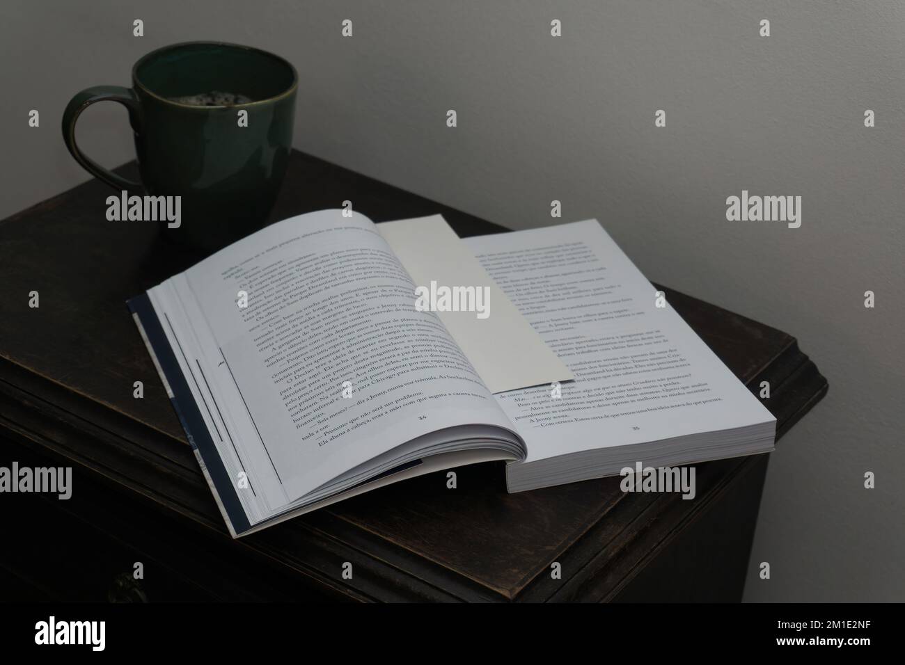 Offenes Buch und Kaffeetasse auf dem Nachttisch Stockfoto