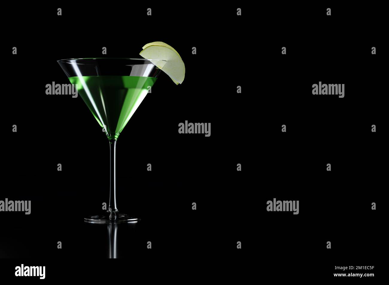 Grüner Appletini-Cocktail mit Apfelgarnierung in martini-Glas auf schwarzem Hintergrund Stockfoto