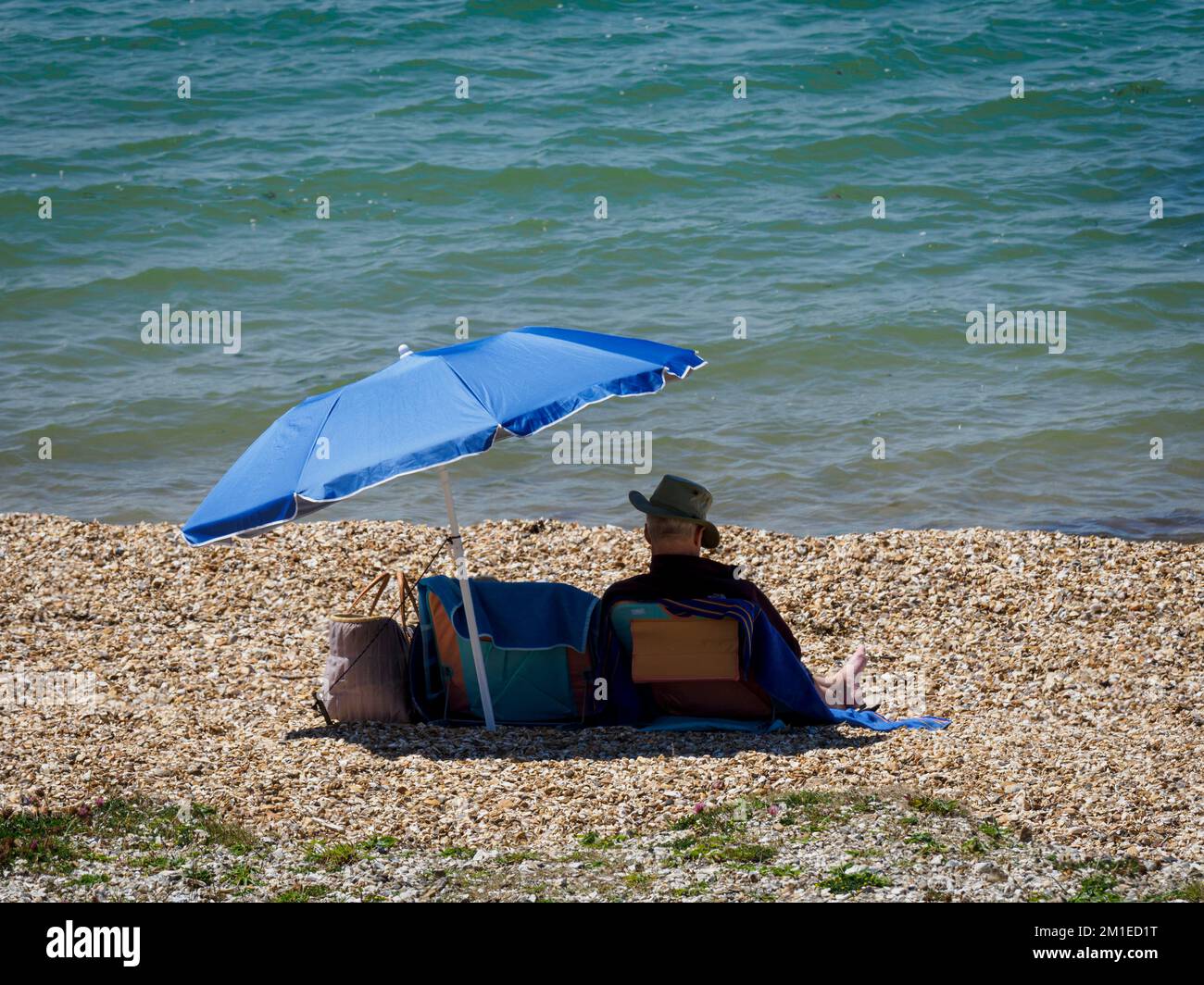 Der Mann saß am Strand in Lee-on-the-Solent, Hampshire, Großbritannien Stockfoto