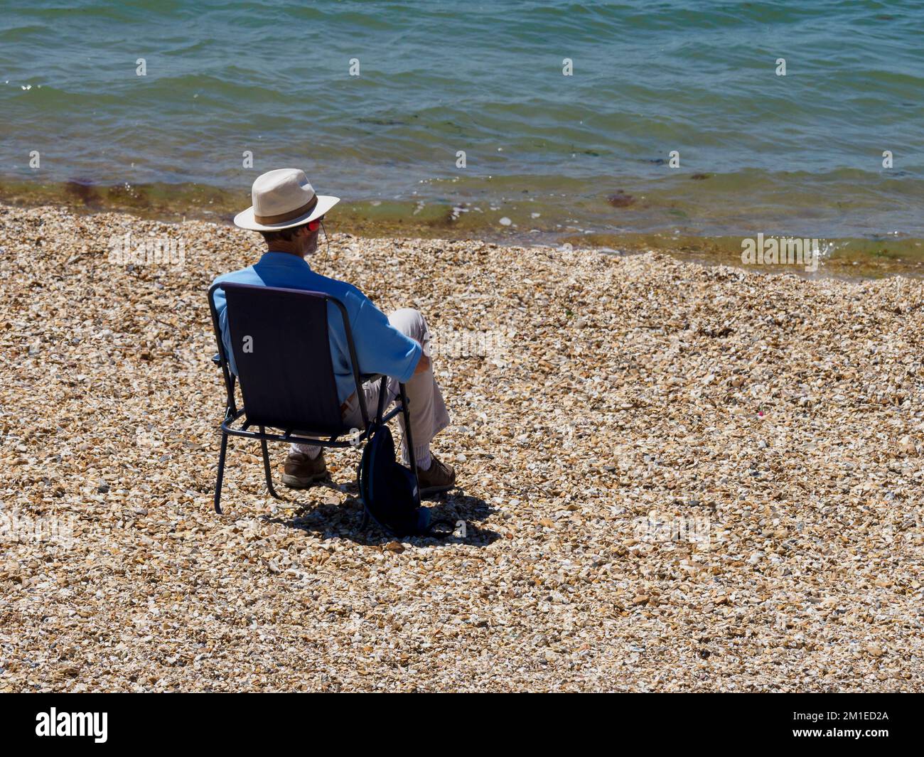 Der Mann saß allein am Strand mit Blick auf Solent, Hill Head Beach, Lee-on-the-Solent, Hampshire, Großbritannien Stockfoto
