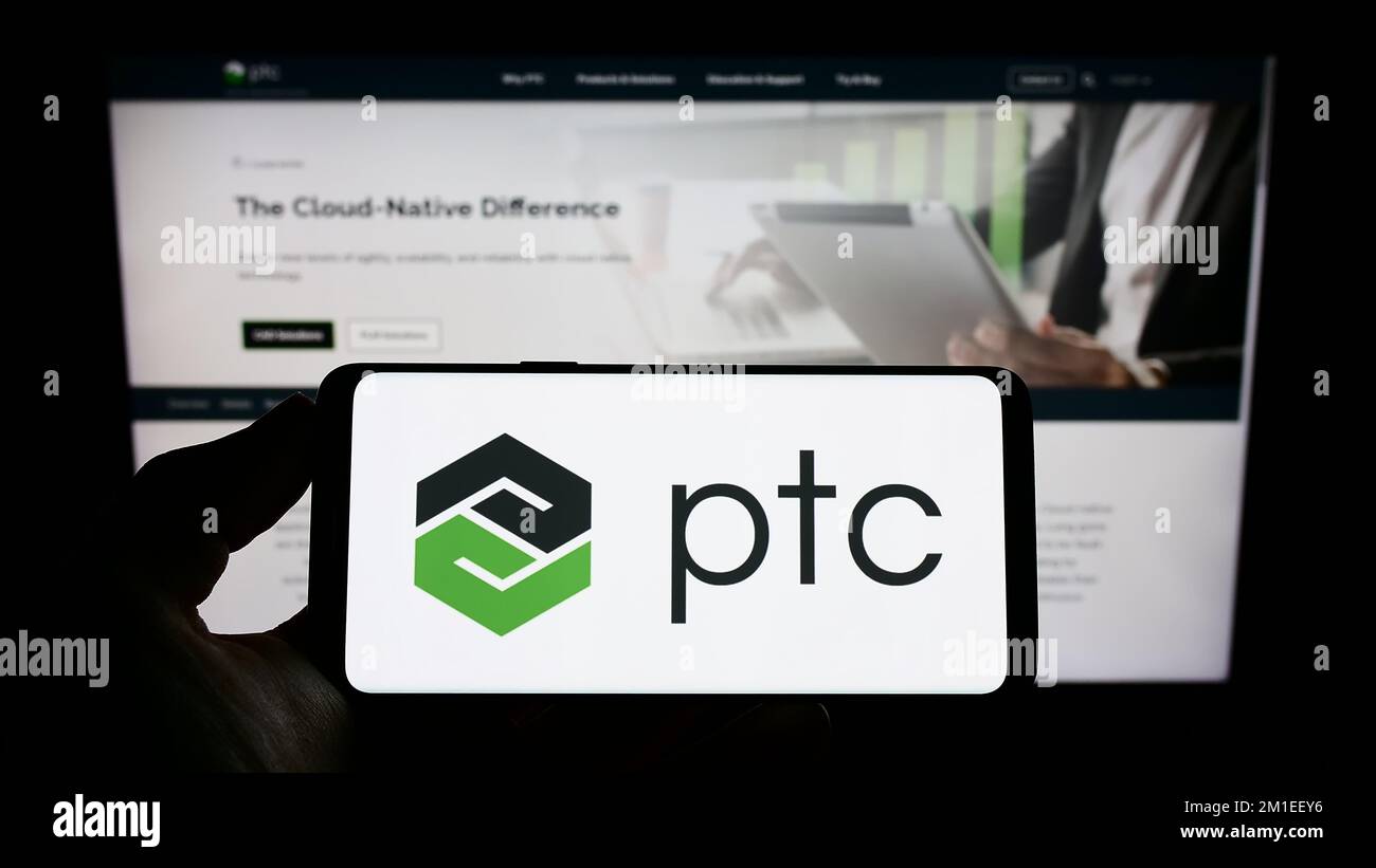 Person, die ein Mobiltelefon mit dem Logo des US-amerikanischen Softwareunternehmens PTC Inc. Auf dem Bildschirm vor der Unternehmenswebseite hält. Konzentrieren Sie sich auf das Display des Telefons. Stockfoto