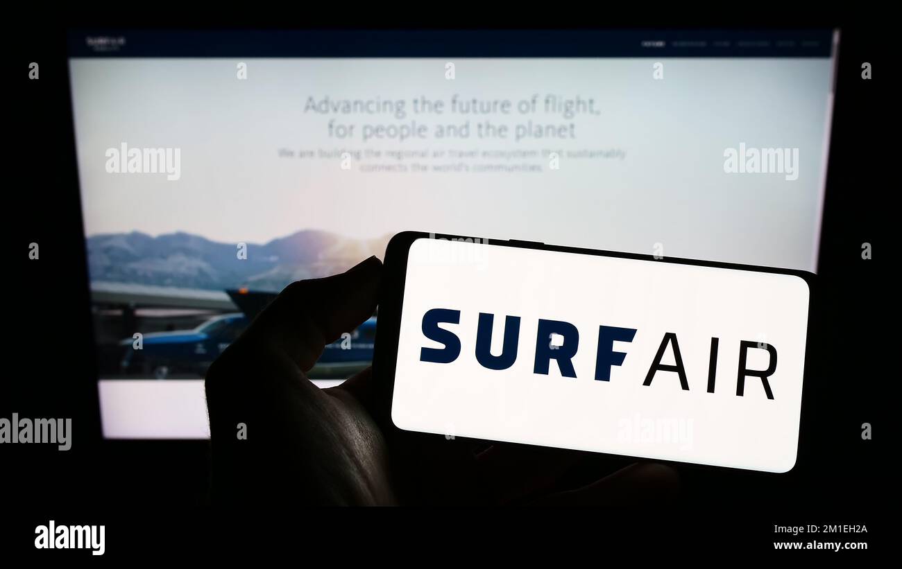 Person, die ein Mobiltelefon mit dem Logo des US-Luftfahrtunternehmens Surf Air Mobility auf dem Bildschirm vor der geschäftlichen Webseite hält. Konzentrieren Sie sich auf das Display des Telefons. Stockfoto