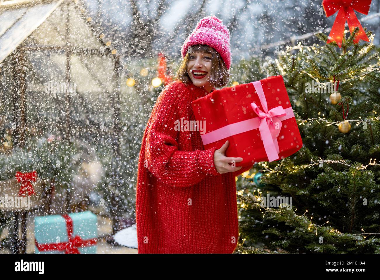 Frau mit einem Geschenk in der Nähe des Weihnachtsbaums im Freien Stockfoto