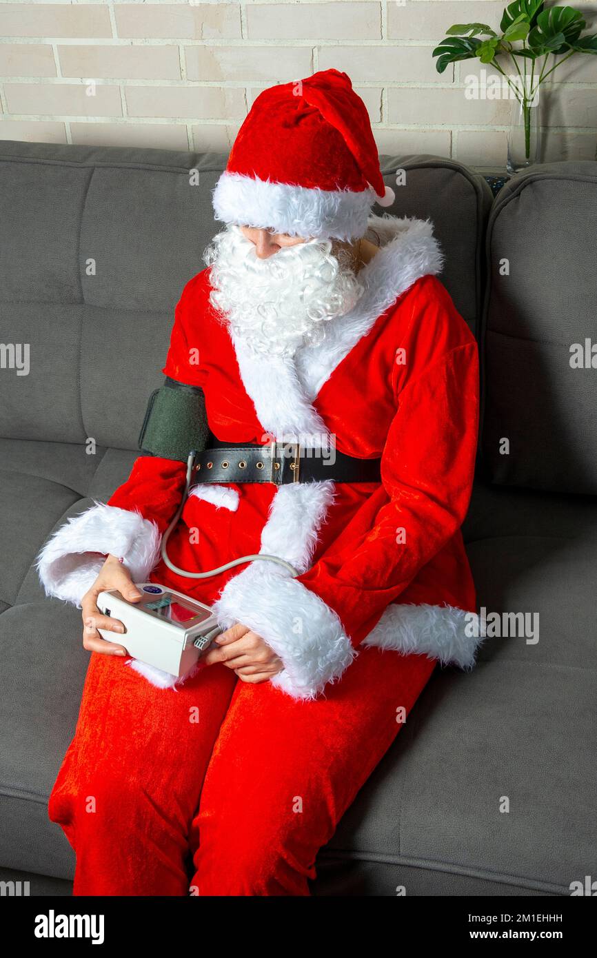 Der Weihnachtsmann ist krank und fühlt sich nicht gut. Der Weihnachtsmann misst den Blutdruck Stockfoto