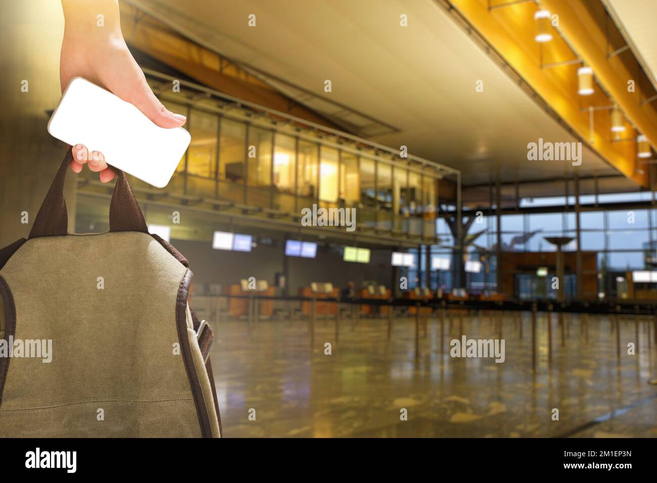 Nahaufnahme einer Hand mit Smartphone und Rucksack. Check-in-Bereich am Flughafen im Hintergrund. Leerer Bildschirm, Sie können Ihre Inhalte einfügen Stockfoto