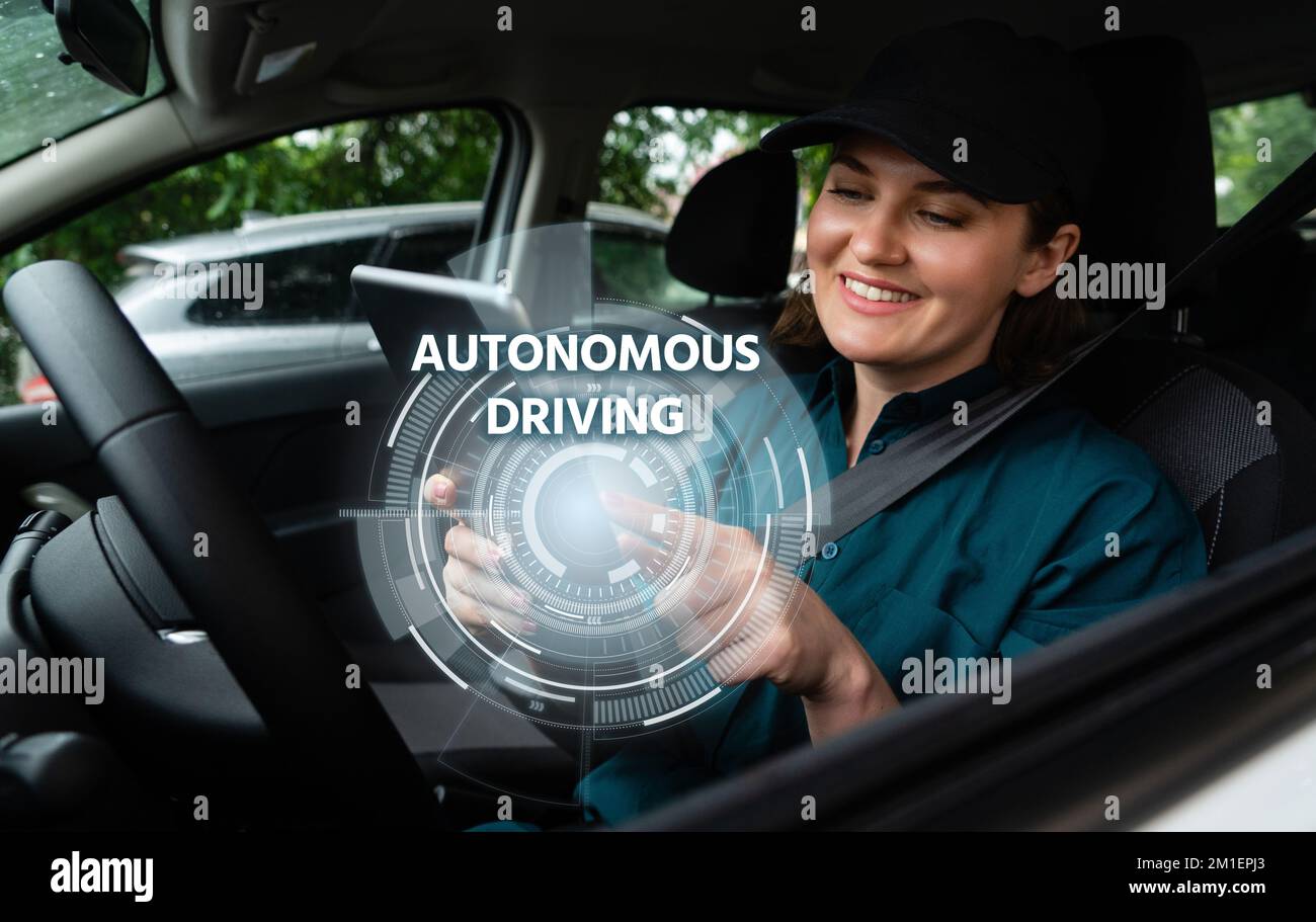 Weibliche Fahrerin steuert ein autonomes Auto mit einem Smartphone Stockfoto