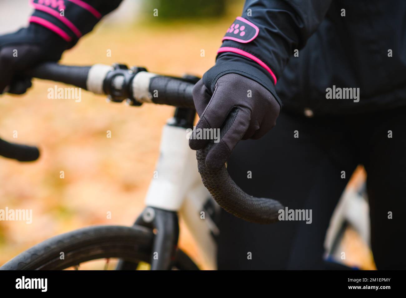 Männliche Hand in Handschuh am Fahrradlenker im Herbst Waldhintergrund während der Fahrt, sportliche Aktivität in der kalten Jahreszeit Stockfoto