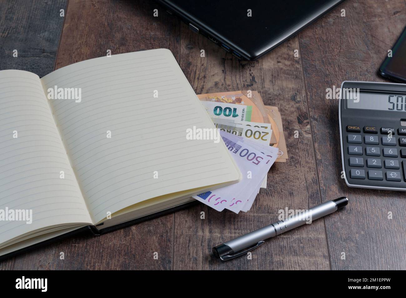 Buchfragment eines Kontogeräts mit Euro-Banknoten und einem Füllfederhalter auf einem Holztisch. Stockfoto