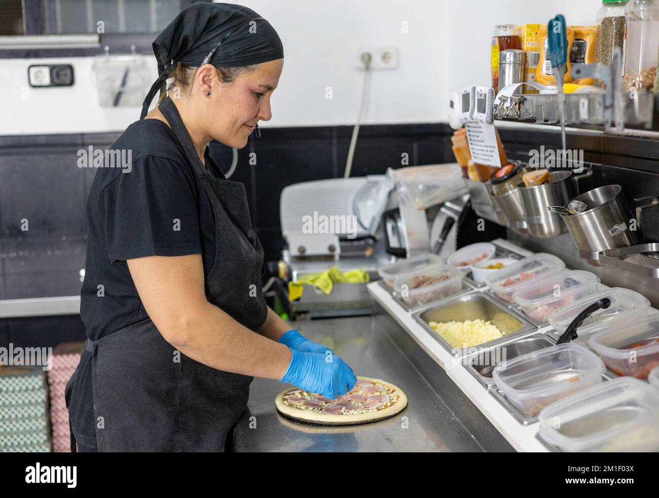 Chefköchin, die Pizza in der Restaurantküche zubereitet Stockfoto