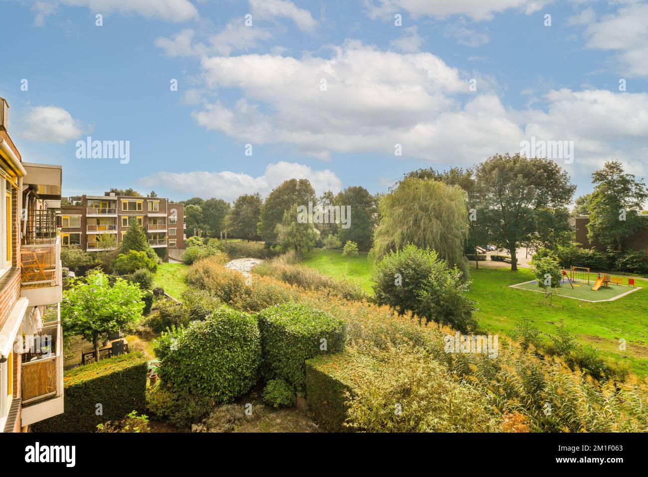 Ein Außenbereich mit Bäumen, Büschen und Rasen im Vordergrund - Bild wurde von meinem Schlafzimmerfenster aufgenommen Stockfoto