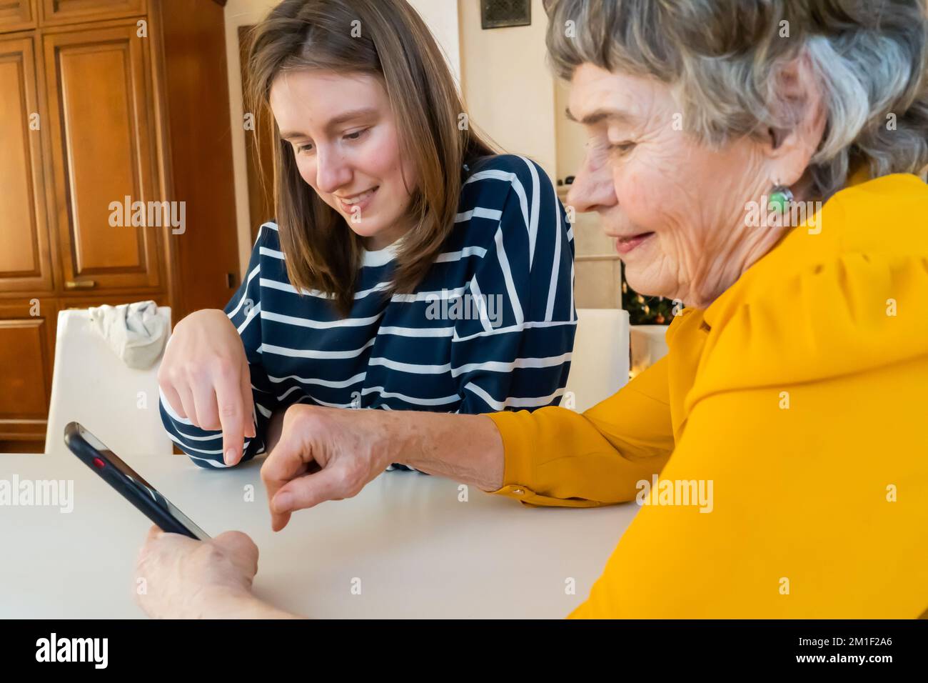 Mädchen hilft ihrer Großmutter mit dem Handy. Stockfoto