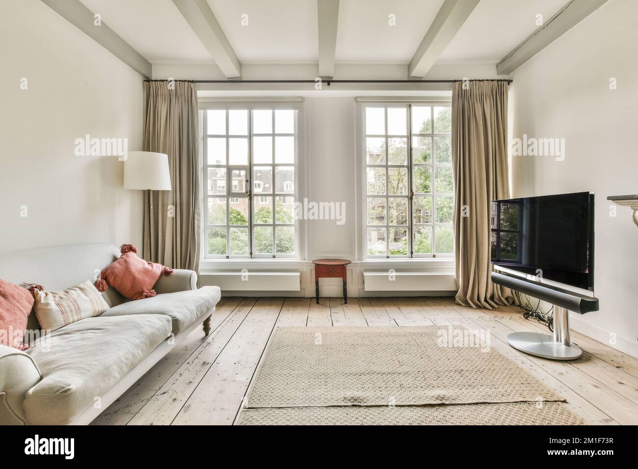 Modernes Bett mit komfortabler Matratze und Sofa in der Nähe von Fernseher und Kamin im geräumigen Schlafzimmer Stockfoto