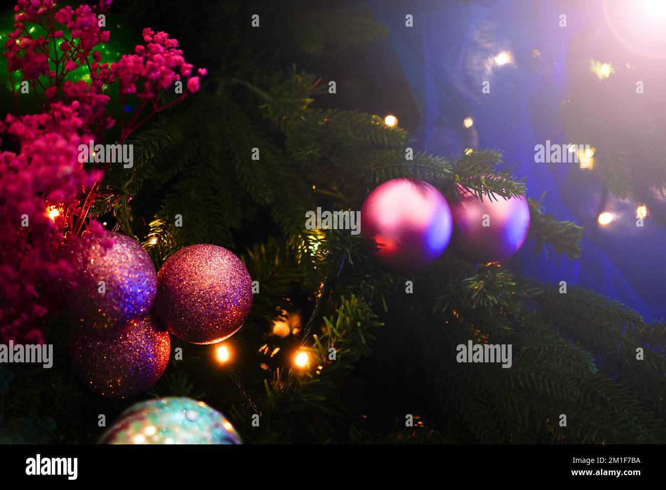 Weihnachtsdekorationen auf dem Weihnachtsbaum. Bunte Kugeln, Girlande, glühende Lampen. Festlicher traditioneller Hintergrund für das neue Jahr Stockfoto