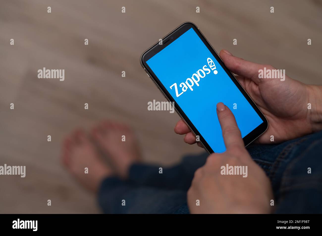 3. Dezember 2022 Almaty Kasachstan: Barfuß Frau mit Smartphone und zappos Logo. Stockfoto