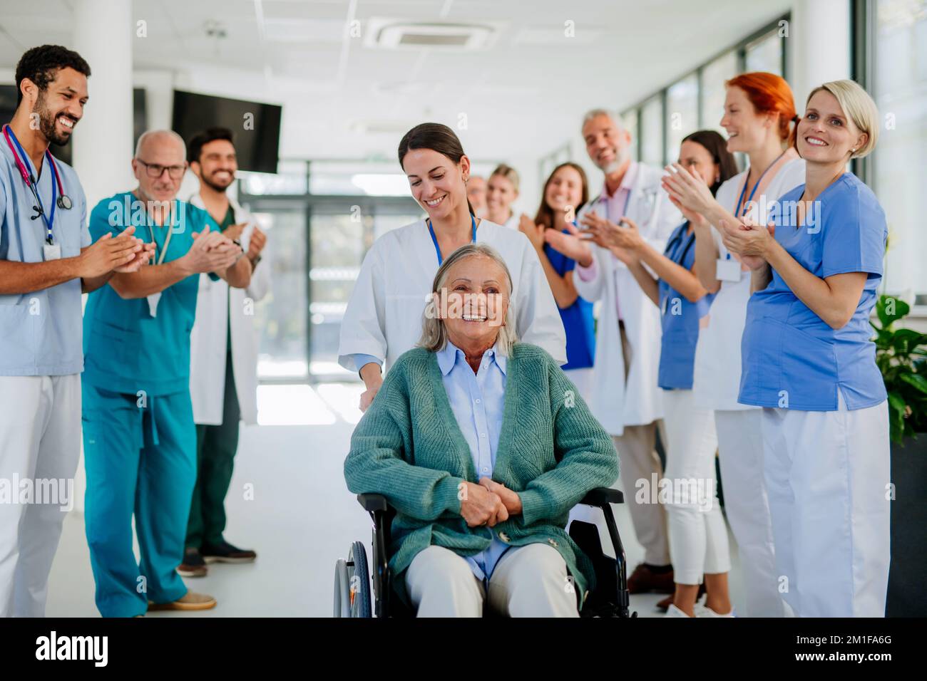 Medizinisches Personal klatscht zu Seniorpatienten, die sich von einer schweren Erkrankung erholt haben. Stockfoto