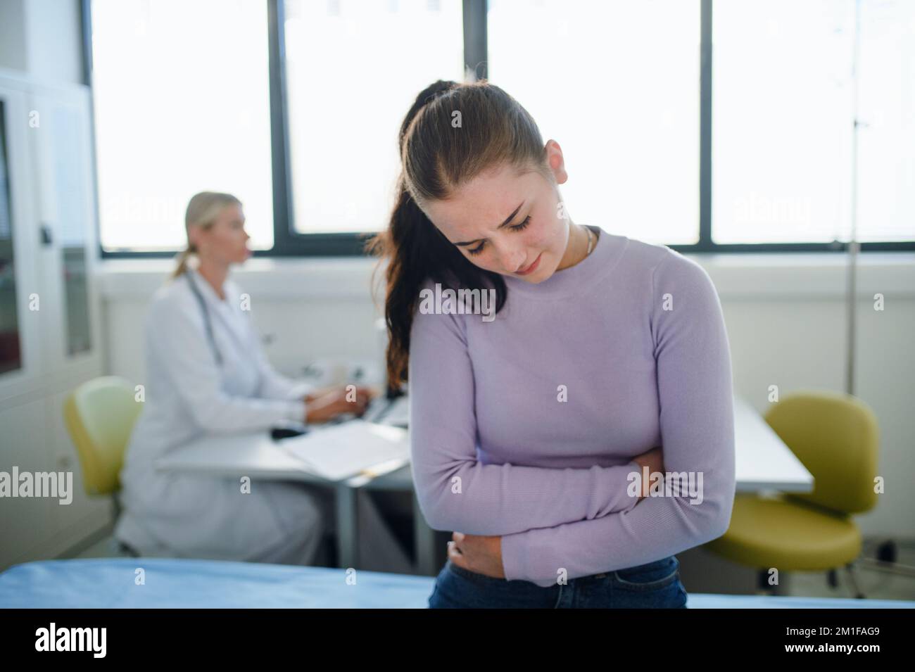 Teenager mit Magenschmerzen sitzt in der Arztpraxis. Stockfoto