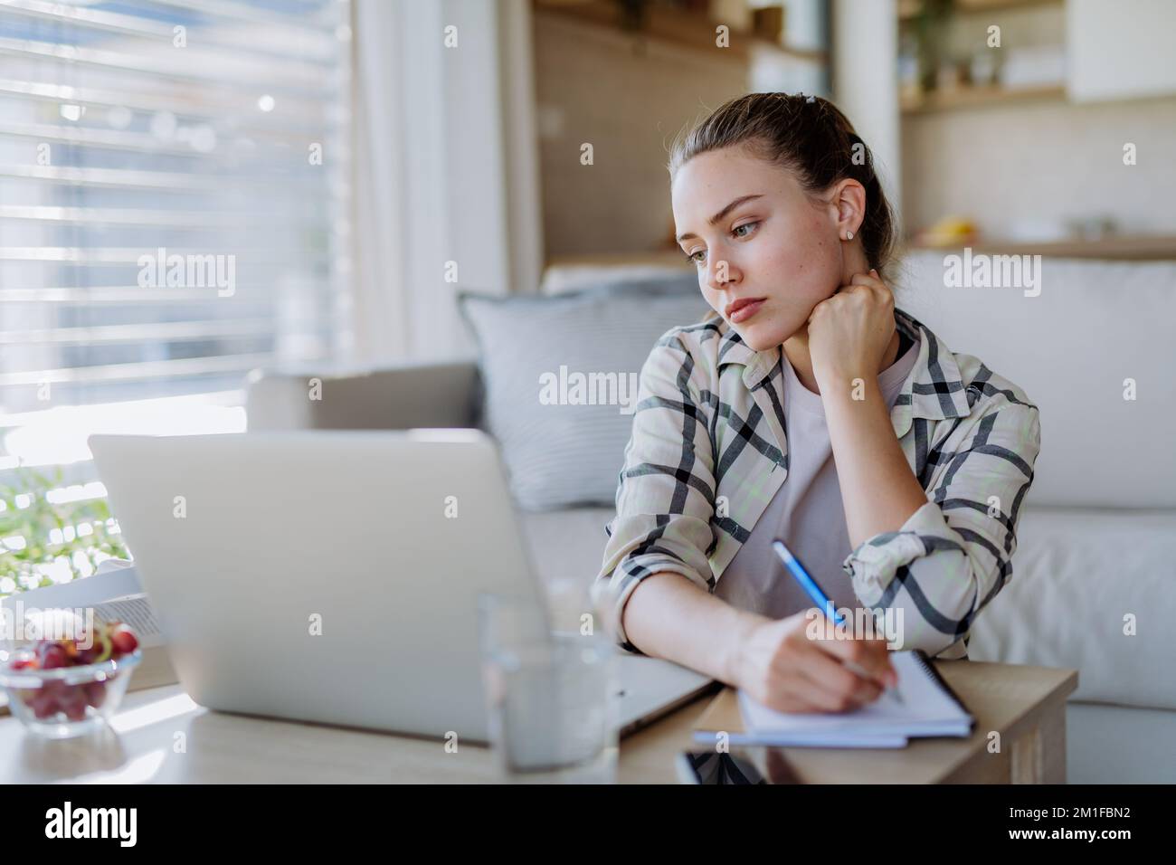 Junge Frau, die Hausaufgaben in ihrer Wohnung hat. Stockfoto