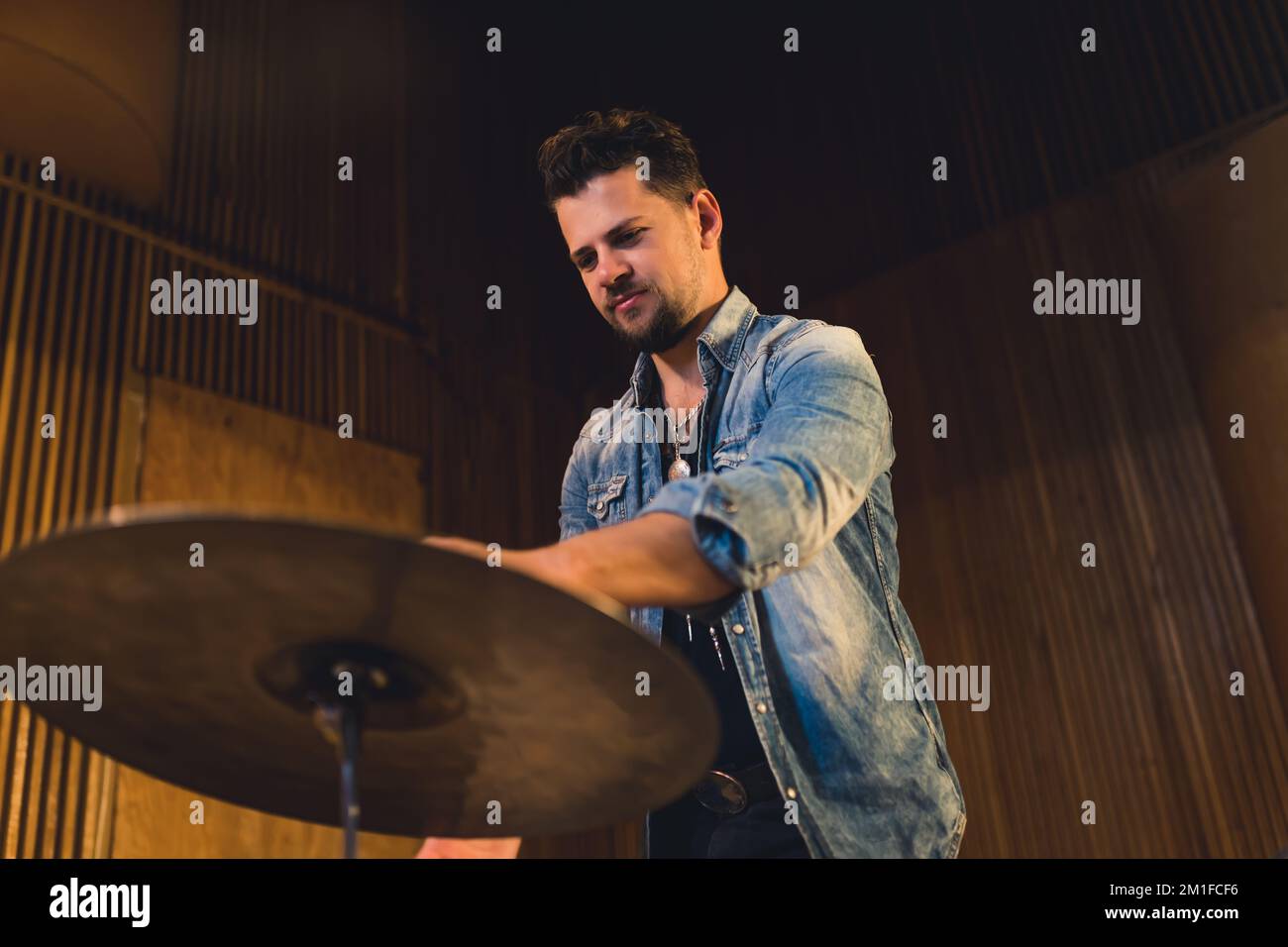 Mittellange Aufnahme eines jungen Schlagzeugers, der auf der Probe spielt, musikalisches Studio-Konzept eines jungen Künstlers. Hochwertiges Foto Stockfoto