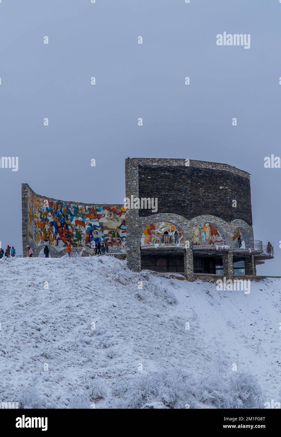 Ein vertikaler Blick auf das Russland-Georgien-Freundschaftsdenkmal in Georgievsk, Georgien, mit Besuchern im Hintergrund im Winter Stockfoto