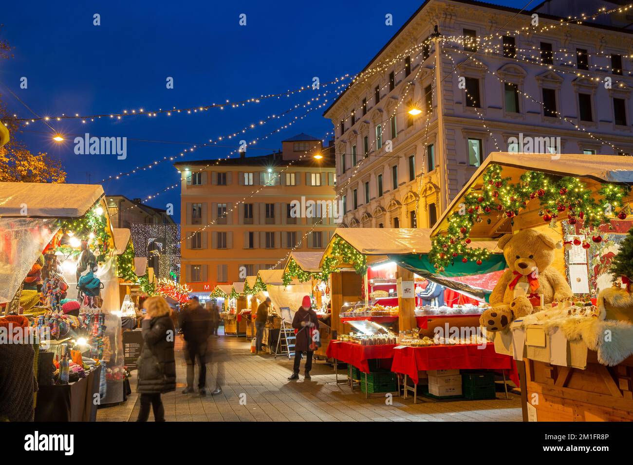 Weihnachtsmarkt in Lugano neben dem Riva Giocondo Albertolli - die Bewegung der Menschen ist verschwommen! Einige Weihnachtsartikel und Blue Hour in t Stockfoto