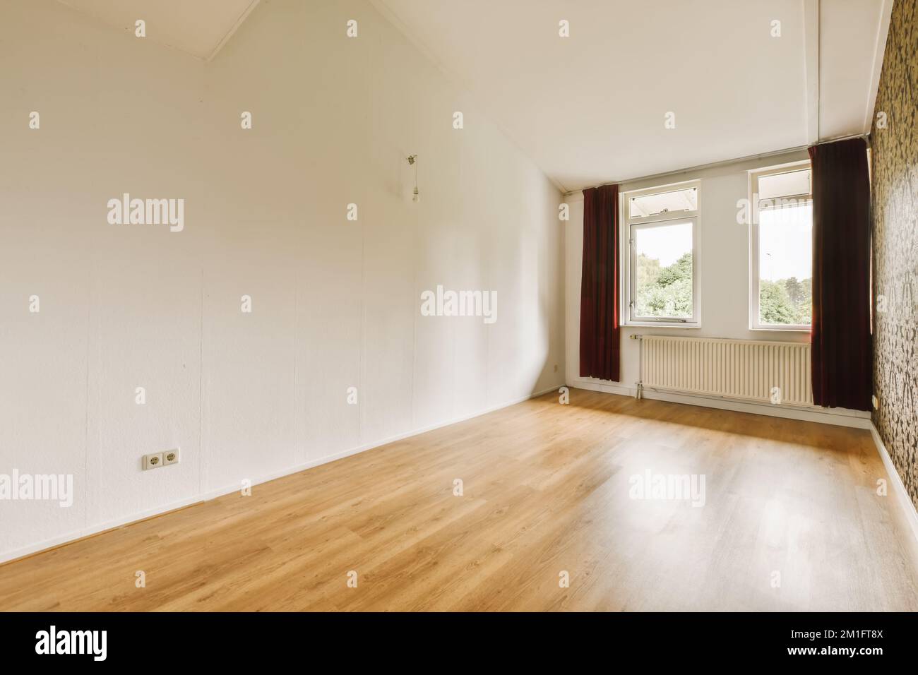 Ein leeres Wohnzimmer mit Holzfußboden und Tapeten an den Wänden in diesem Wohnbereich Stockfoto