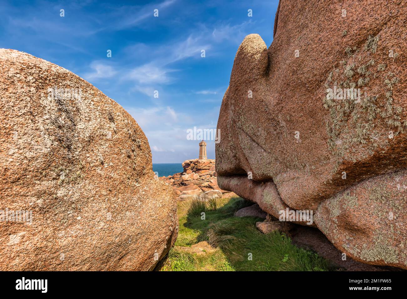 Malerischer Blick auf den Men Ruz Leuchtturm in der Bretagne Frankreich zwischen zwei riesigen roten Felsen Stockfoto