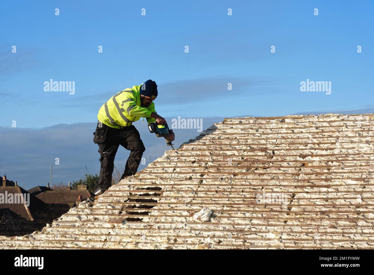 Bauunternehmer, der die Dämmung aus gehärtetem Spritzschaum aus dem Dachbereich eines Vorstadthauses, Shepperton Surrey England UK, entfernt Stockfoto