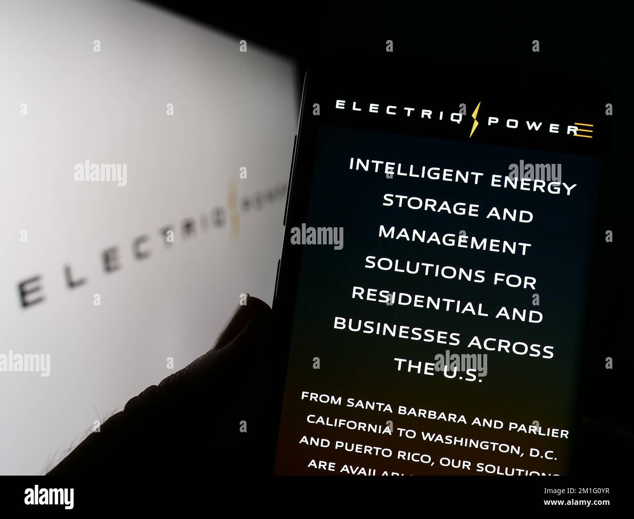 Person, die ein Mobiltelefon mit einer Webseite des US-amerikanischen Energiespeicherunternehmens Electriq Power Inc. Auf dem Bildschirm mit Logo hält. Konzentrieren Sie sich auf die Mitte des Telefondisplays. Stockfoto