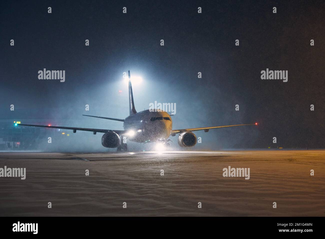 Winternacht am Flughafen. Das Flugzeug rollt bei starkem Schneefall zur Startbahn. Stockfoto