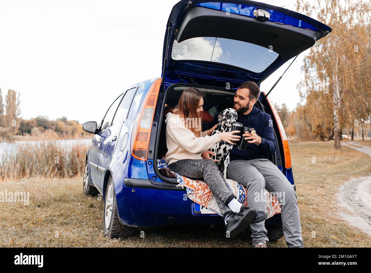 Mann mit Frau, viel Spaß mit ihrem Hund draußen im Wald in der Nähe des Autos. Stockfoto