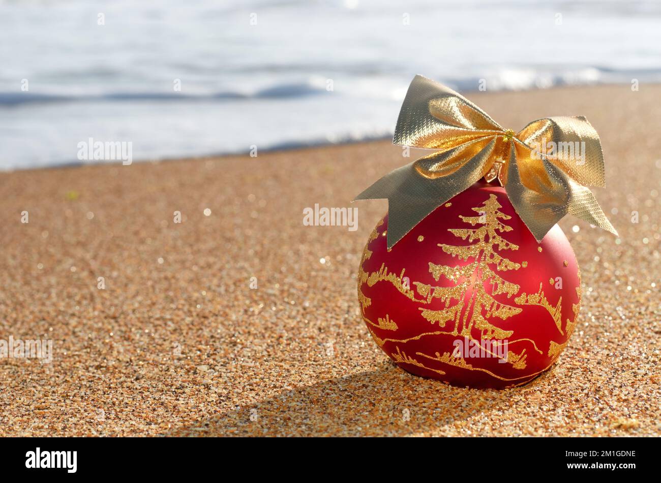 Weihnachtsbaumdekoration am Strand Sand vor dem Hintergrund von Meereswellenschaum Stockfoto
