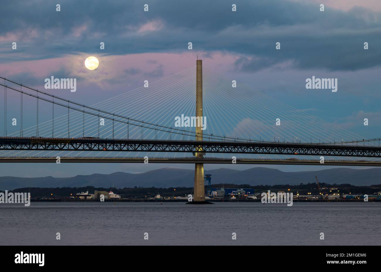 In Blue Hour, Firth of Forth, Schottland, Großbritannien, geht ein Vollmond über die Brücken Queensferry Crossing und Forth Road Stockfoto