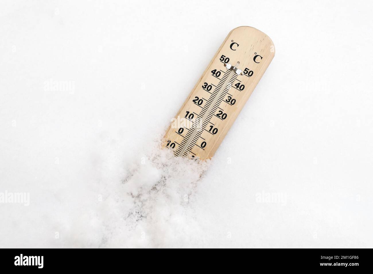 Holzthermometer auf Schnee zeigt niedrige Temperaturen unter Null in grad celsius an. Winterfrost. Wettervorhersagekonzept. Flach liegend, Draufsicht Stockfoto