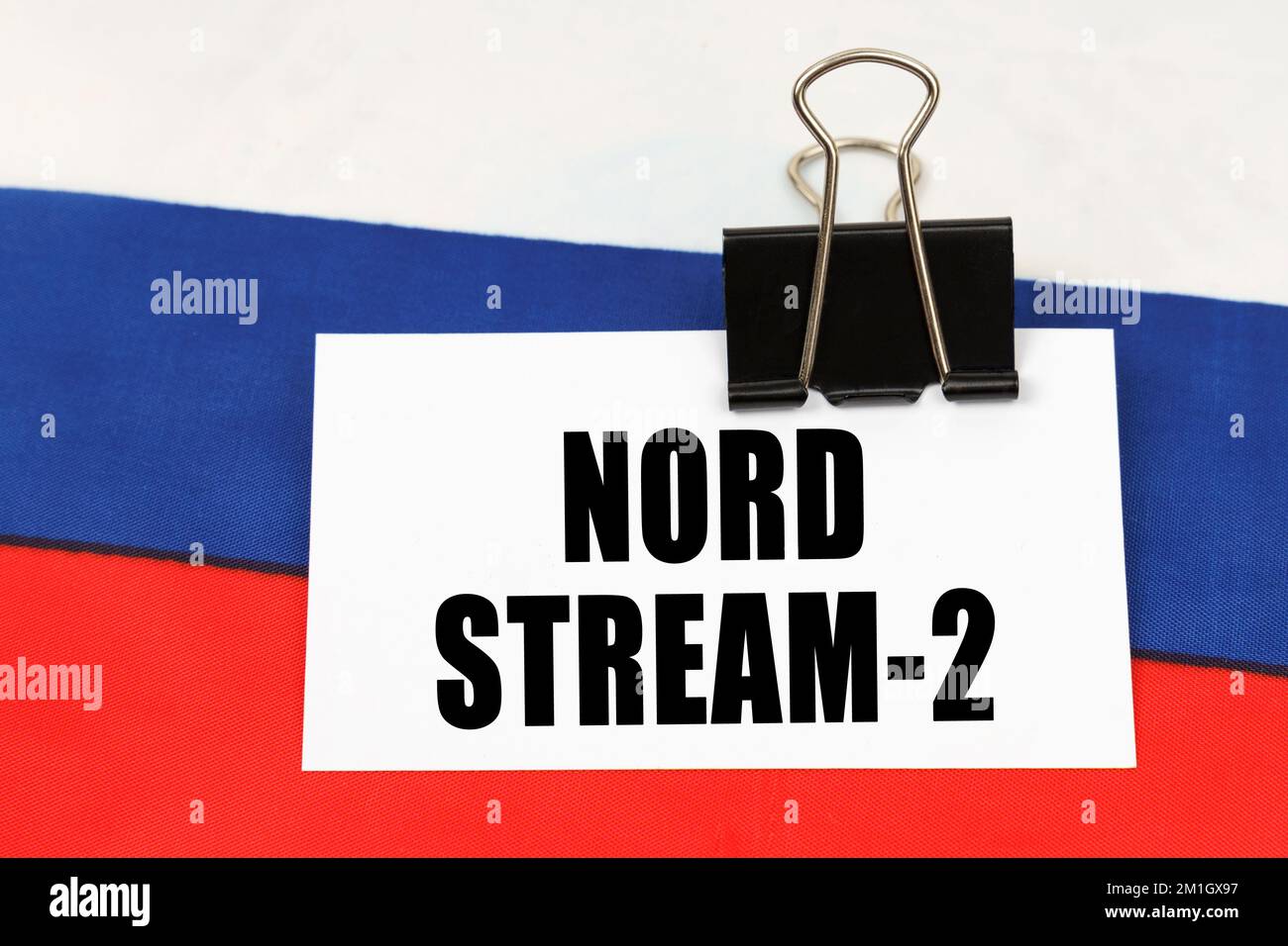 Nationales Konzept. Auf der russischen Flagge befindet sich eine Visitenkarte mit der Aufschrift Nord Stream 2 Stockfoto