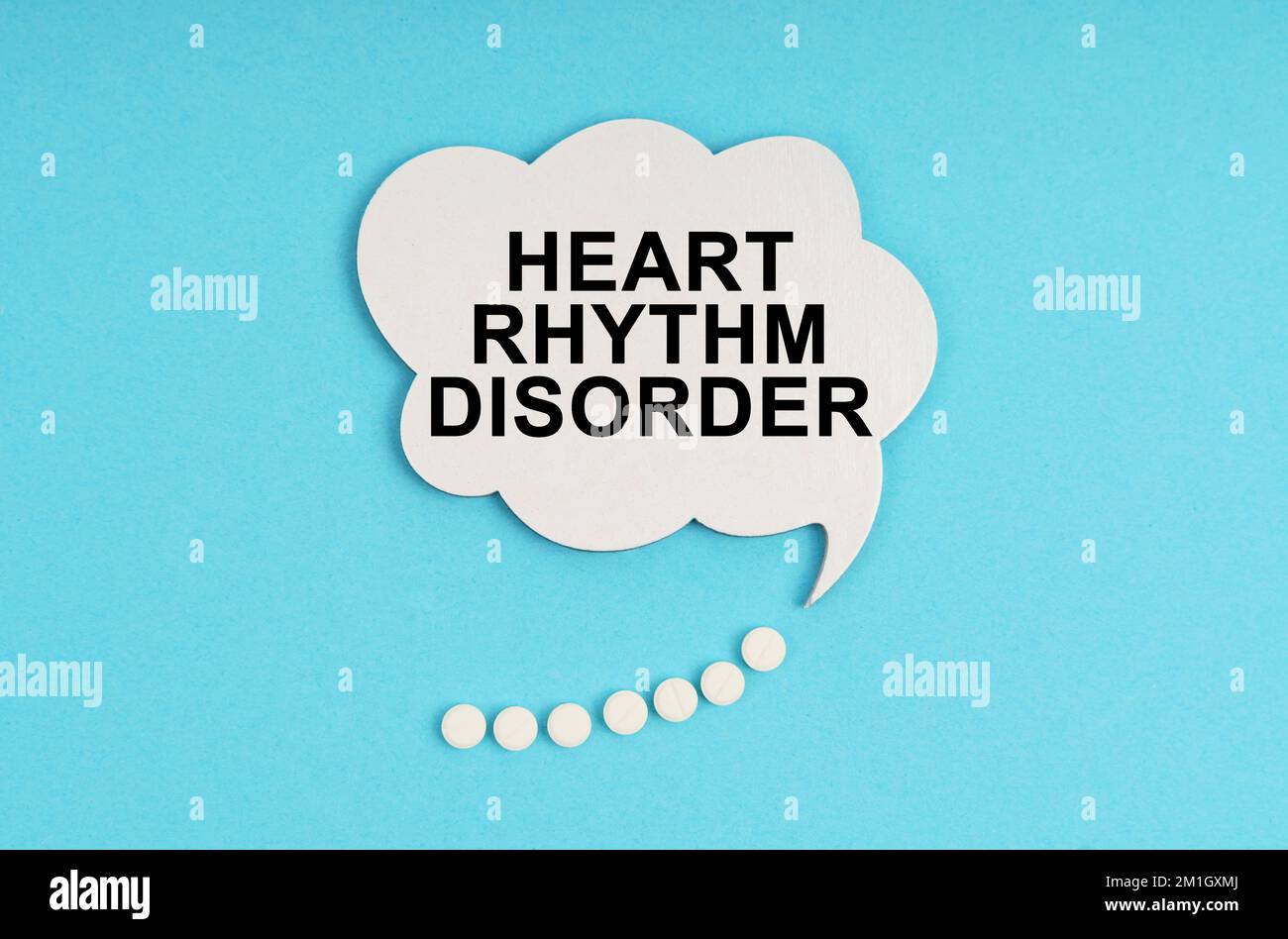 Medizin und Gesundheitskonzept. Auf einem blauen Tisch sind Pillen und ein weißer Teller mit der Inschrift - Herzrhythmusstörung Stockfoto
